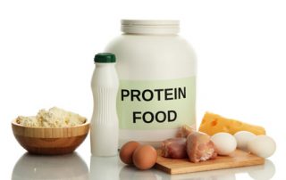 Large jar of protein poweder surrounded by protein foods