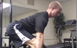Man wearing black deadlifting weight in gym with exercise equipment in background