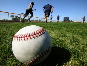 Men running on baseball field on sunny day with baseball in foreground
