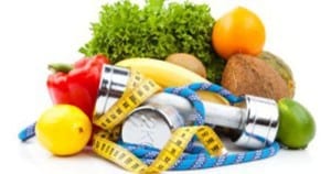Pile of healthy lemon, red pepper, banana, lime, oranges, leafy green, coconut, and other healthy fruit and vegetables with yellow tape measure, blue rope, and 2kg silver barbells