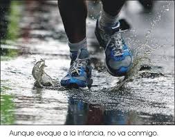 Man running through puddles in blue and gray running shoes with Spanish subtitles