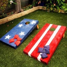 American Flag decorated corn hole boards on trim green lawn with landscaped border