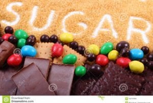 Pile of chocolate, cookies, candy and brown cane sugar with word "sugar" spelled out