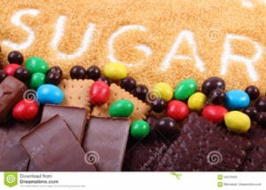 Pile of chocolate, cookies, candy and brown cane sugar with word "sugar" spelled out