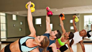 Workout class of men and women with kettle bells in gym