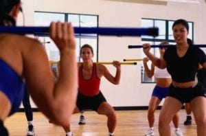Women's class dead lifting bar in a gym