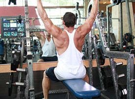 Muscular man lifting barbell on blue bench in gym