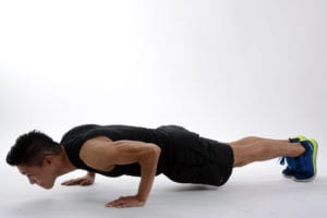 Young man dressed in black workout clothes doing push ups