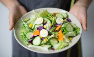 Person in gray holding healthy salad on white plate