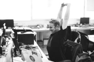 Black and white picture of man stretching arms at desk