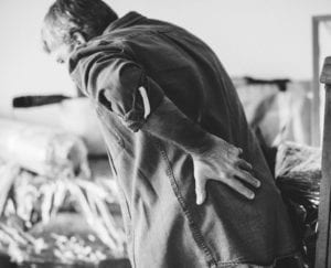 Man holding lower back in pain while bending over