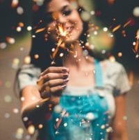 Dark hair woman in overalls holding a sparkler