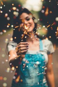 Dark hair woman in overalls holding a sparkler
