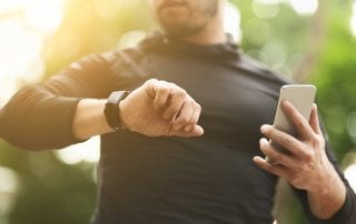 man checking his fitness tracker on his fitness watch during a run