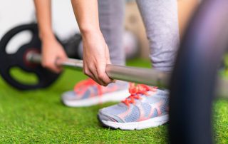 Close up of someone grabbing barbell off floor