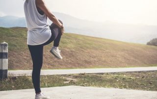 Athlete woman doing some stretching exercises legs before running on outdoor.