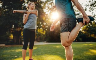 Shot of young man and woman stretching in the park.