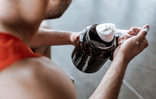 Man holding protein powder in scoop over bottle