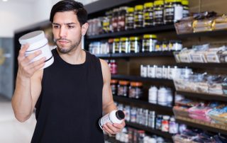 Serious young sportsman looking sport dietary supplements in store