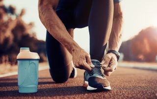 Young male jogger athlete training and doing workout outdoors in city.